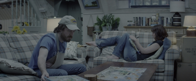 Wide shot frame from 10 Cloverfield Lane — sitting, book, room