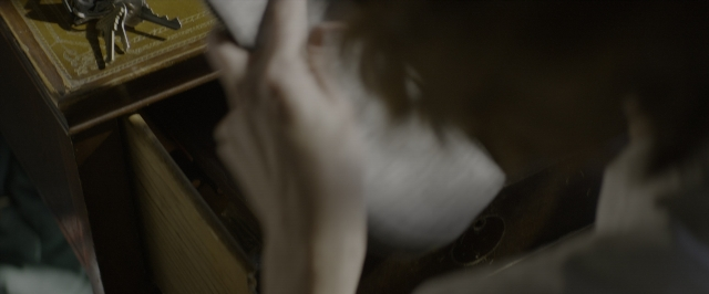 Wide shot frame from 10 Cloverfield Lane — sitting, table, hand