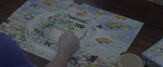 Wide shot frame from 10 Cloverfield Lane — table, hand, fish