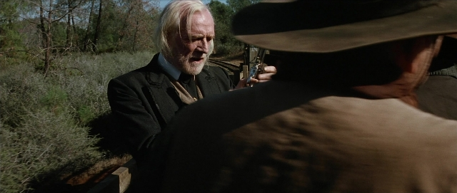 Wide shot frame from Unforgiven — standing, hat, coat