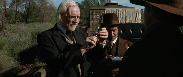 Wide shot frame from Unforgiven — standing, hat, coat
