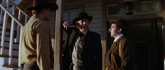 Wide shot frame from Unforgiven — standing, dialogue, hat