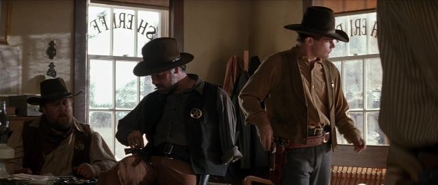 Wide shot frame from Unforgiven — sitting, standing, room