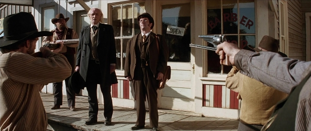 Wide shot frame from Unforgiven — standing, dialogue, door