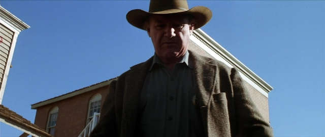 Wide shot frame from Unforgiven — standing, hat, coat
