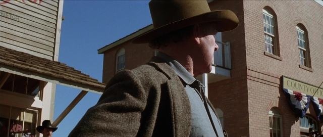 Wide shot frame from Unforgiven — standing, hat, coat