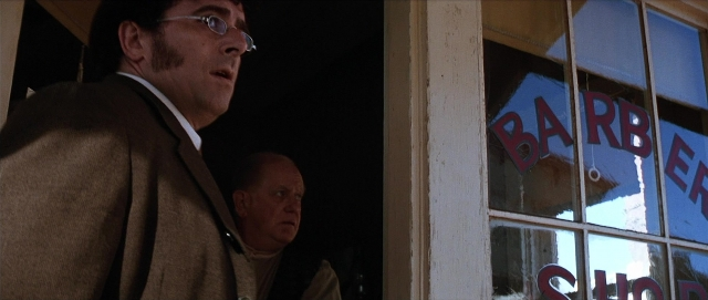 Wide shot frame from Unforgiven — standing, dialogue, coat