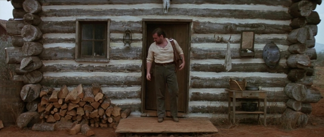 Medium shot frame from Unforgiven — standing, table, door