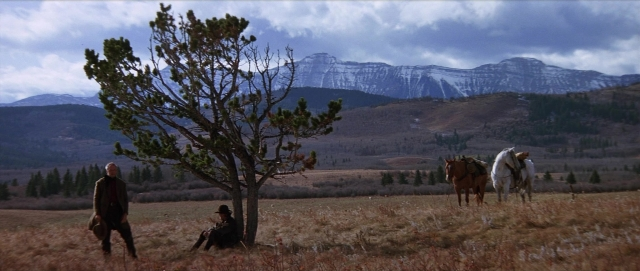 Wide shot frame from Unforgiven — sitting, standing, hat