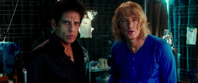 Wide shot frame from Zoolander 2 — standing, room, table