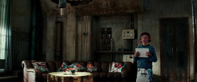 Wide shot frame from Zoolander 2 — standing, room, table