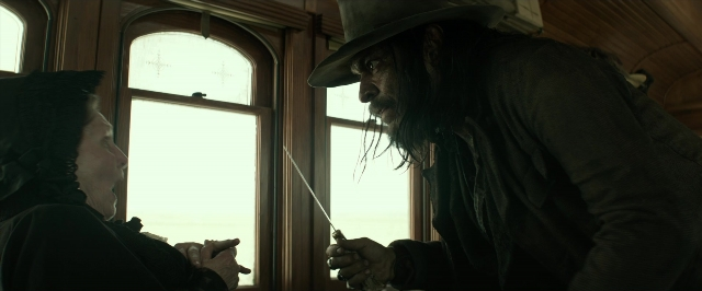 Wide shot frame from The Lone Ranger — sitting, table, hat