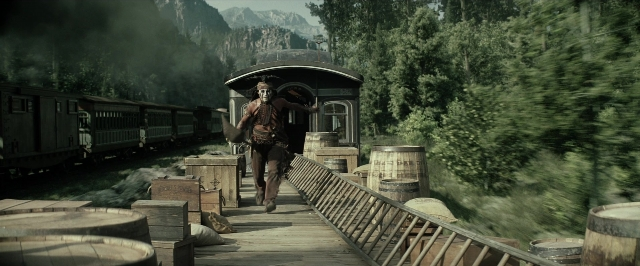 Wide shot frame from The Lone Ranger — walking, train, barrel