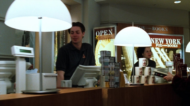 Wide shot frame from You've Got Mail — sitting, desk, standing