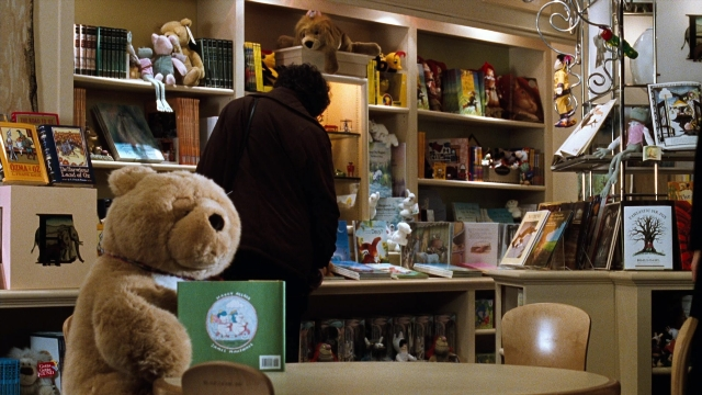 Wide shot frame from You've Got Mail — sitting, book, standing