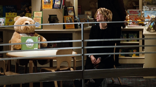 Wide shot frame from You've Got Mail — sitting, book, table