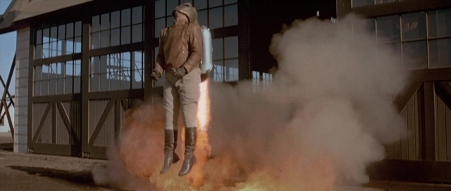 Wide shot frame from The Rocketeer — standing, fire, hand
