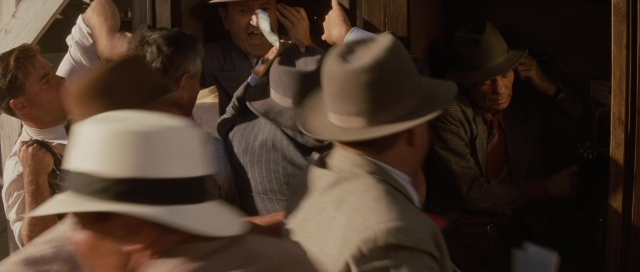 Wide shot frame from The Rocketeer — dialogue, door, hat
