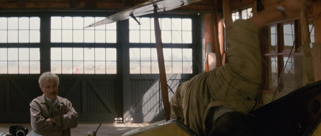 Wide shot frame from The Rocketeer — standing, mustache, airplane