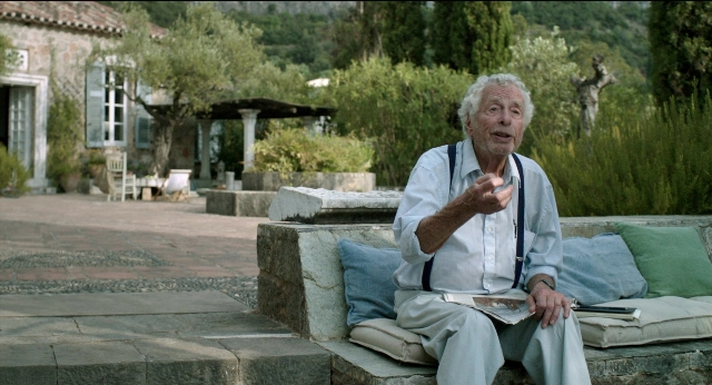 Wide shot frame from Before Midnight — sitting, book, shirt