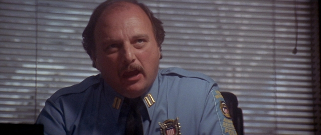 Medium shot frame from Die Hard 2 — sitting, uniform, office