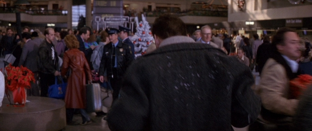 Wide shot frame from Die Hard 2 — standing, walking, table