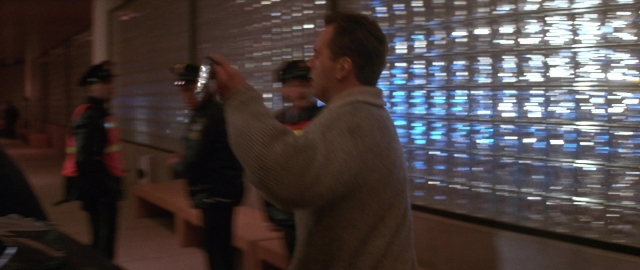 Wide shot frame from Die Hard 2 — standing, room, hand