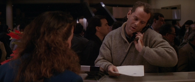 Wide shot frame from Die Hard 2 — sitting, standing, dialogue