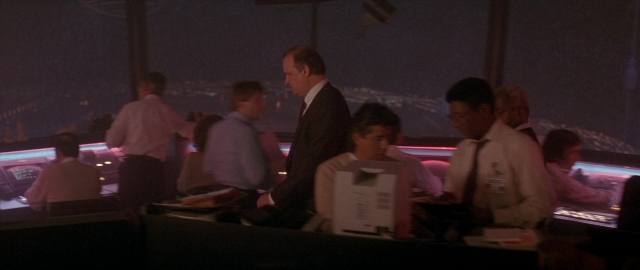 Wide shot frame from Die Hard 2 — sitting, standing, room