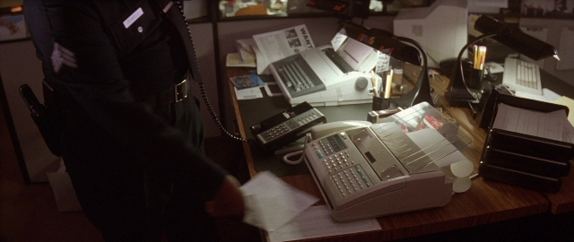 Wide shot frame from Die Hard 2 — phone, uniform, hand