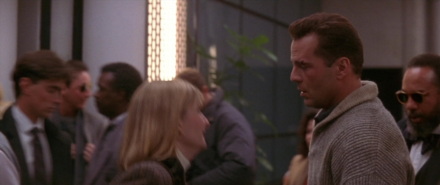 Wide shot frame from Die Hard 2 — room, suit, beard