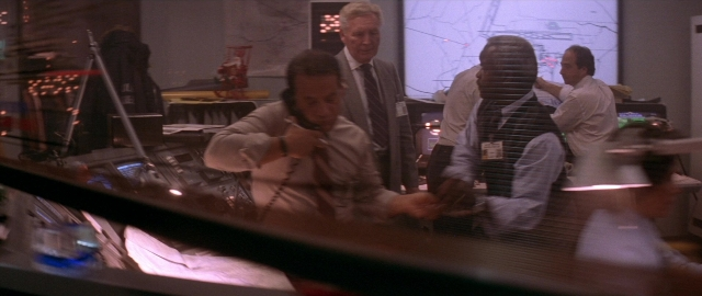 Wide shot frame from Die Hard 2 — sitting, standing, room