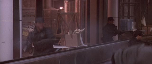 Wide shot frame from Die Hard 2 — sitting, standing, room