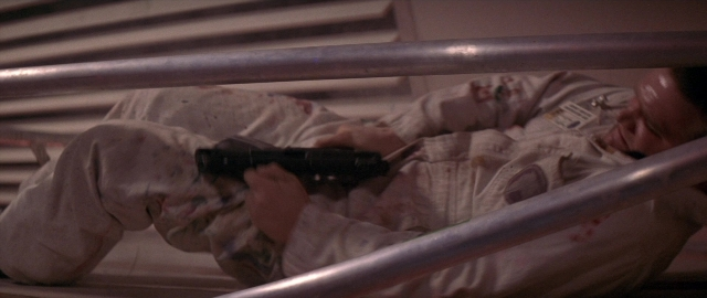 Wide shot frame from Die Hard 2 — room, hand, gun