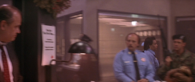 Wide shot frame from Die Hard 2 — room, dialogue, suit