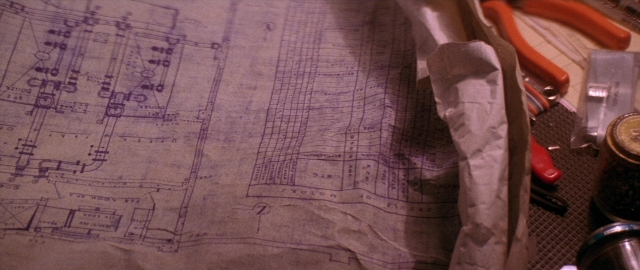 Wide shot frame from Die Hard 2 — sitting, table, scissors