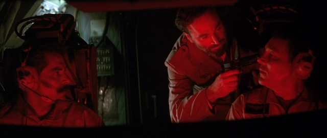 Wide shot frame from Die Hard 2 — room, dialogue, gun