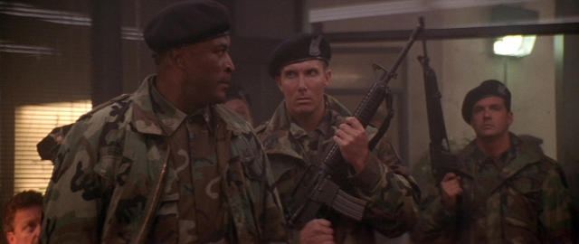 Wide shot frame from Die Hard 2 — standing, dialogue, door