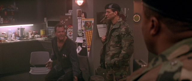 Wide shot frame from Die Hard 2 — sitting, standing, room