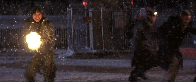 Wide shot frame from Die Hard 2 — street, hat, fire