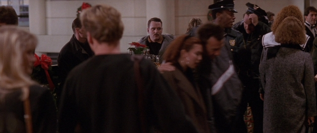 Wide shot frame from Die Hard 2 — standing, room, table