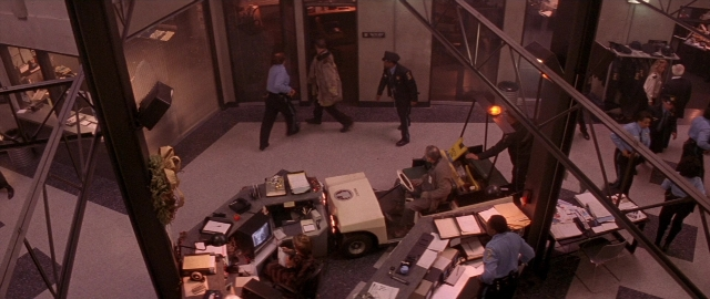 Wide shot frame from Die Hard 2 — sitting, book, standing