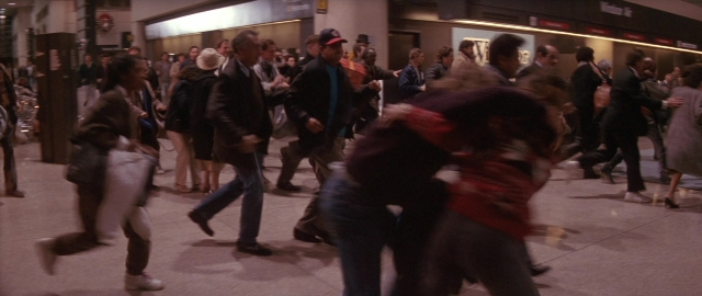 Wide shot frame from Die Hard 2 — walking, street, hat