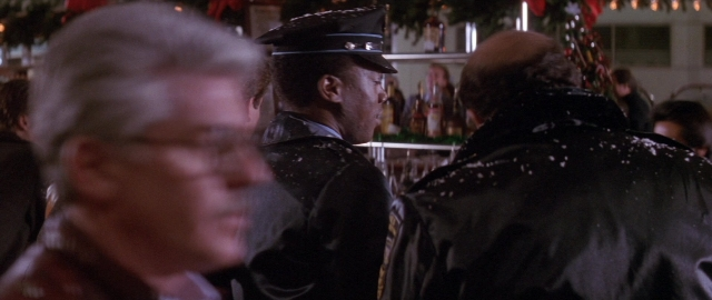Wide shot frame from Die Hard 2 — standing, street, hat