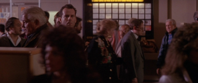 Wide shot frame from Die Hard 2 — standing, room, suit