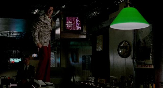 Wide shot frame from The King of Comedy — sitting, standing, hand