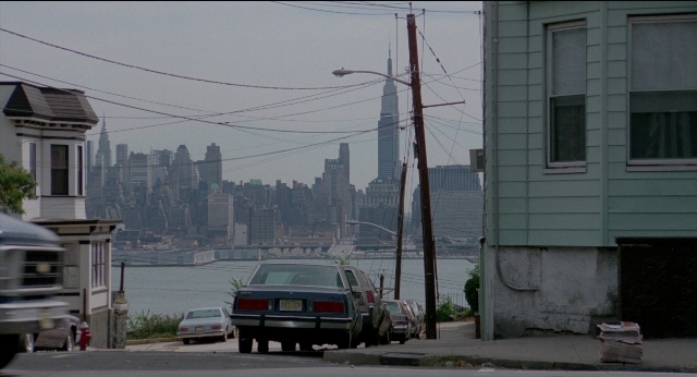 Wide shot frame from The King of Comedy — street, car, house