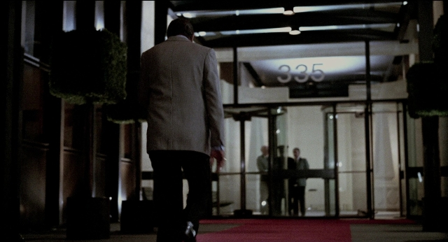 Wide shot frame from The King of Comedy — walking, door, suit