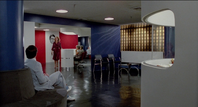 Wide shot frame from The King of Comedy — sitting, standing, table