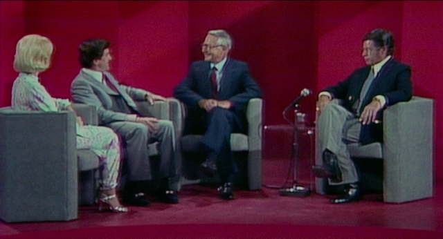 Wide shot frame from The King of Comedy — sitting, dialogue, suit
